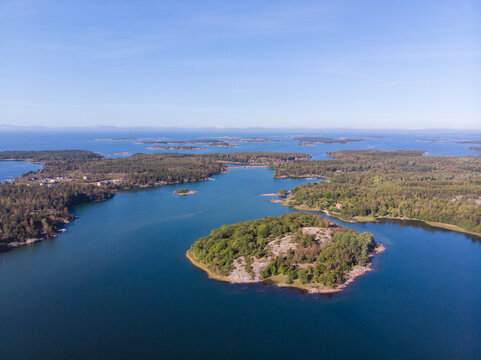Stunning aerial view of a coastal archipelago with scattered islands surrounded by clear blue waters under a vibrant summer sky. Idyllic nature scene perfect for travel and exploration.