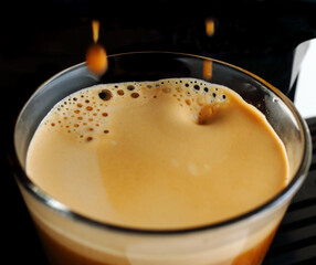 Close-up of fresh espresso coffee, pouring from coffee machine. Selective shallow focus