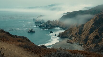 A misty coastal landscape featuring rock formations and the vast ocean