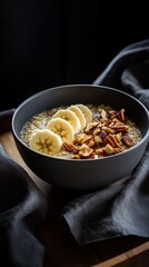 Warm bowl of quinoa porridge with banana and pecans on dark fabric  