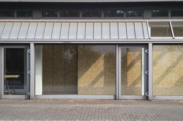 Boarded up storefront windows reflecting sunlight on empty building