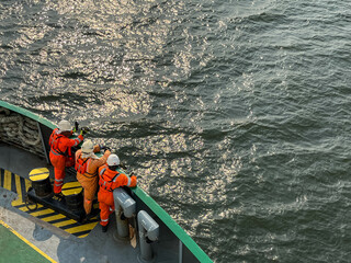 Seafarers are looking forward from the forward station of the offshore support vessel, waiting for ship arrival to port jetty to start mooring operations or to drop the anchor on approaches to berth