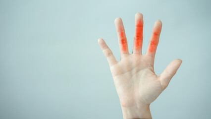 Fototapeta premium Hand with red paint on fingers open palm isolated on light background concept of creativity art or warning minimal style copy space emotional expression of alertness