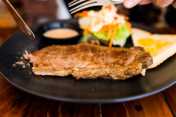 Use fork and knife eating grilled pork chop. Close up