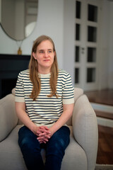 A visually impaired woman with blond hair relaxing in an armchair in her modern home
