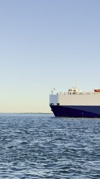 Vehicle carrier or RO-RO ship sailing with tugboat into port