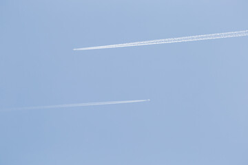 Contrails of two airplanes high in the sky. Aircraft of airline spraying chemtrails. Travel jet for transportation of people