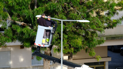 Utility workers repairing street light with hydraulic lift in