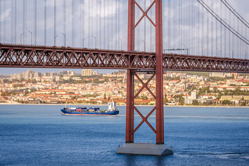 Container ship passing under 25 de Abril bridge, Lisbon, Portugal on