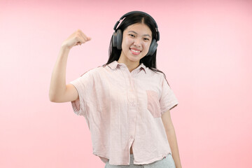 young asian woman enjoying with her headphone in pink studio background