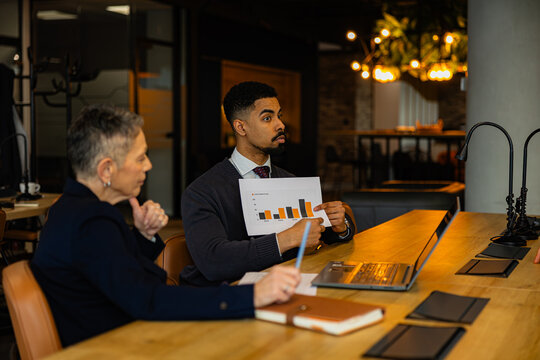 Business colleagues discussing company performance and analyzing financial charts during a meeting in the office