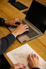Business colleagues working together, analyzing financial data on charts and using laptop, during a productive office workday