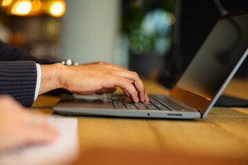 Close up of male hands typing on a laptop keyboard, focused on work tasks in a modern office environment, showcasing productivity and efficiency