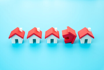 The overturned red house stands out from the row. Home insurance. Construction regulation and re-checking of buildings for compliance. Housing regulation, structural inspections, or policy reviews.