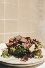 Sandwich with meat, egg and with freshly greens. Crop delicious breakfast served on wooden table in...