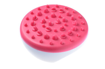 Textured red rubber massage brush for body care on white background