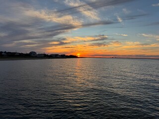 Sunset over calm ocean waters in the Ocean View area of Norfolk, Virginia with shoreline homes and a golden sky