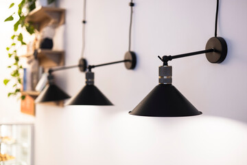 Black lamps on the wall in a bright cafe interior.