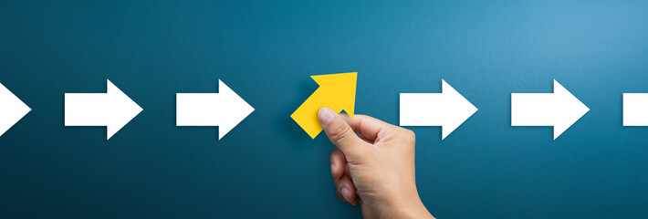 Group of arrows in one direction and businessman hand holding arrow pointing in the different way. Business concept for new ideas creativity and innovative solution