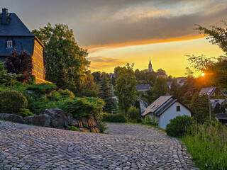 peaceful village or town glows in the golden light of sunset, with cobblestone streets, rustic...