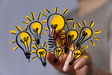 Hand holding multiple glowing lightbulbs, symbolizing innovation, creativity, and brainstorming.