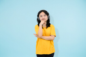 young asian woman thinking with her headphone in studio background