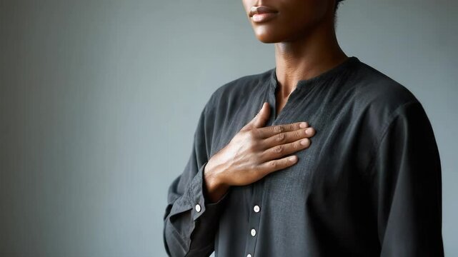A man's hand gently resting on his chest, conveying sincerity and inner peace.