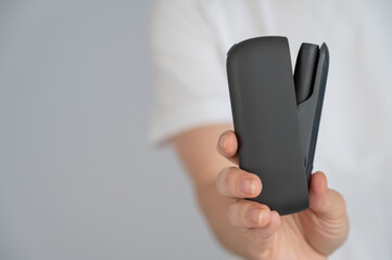 A woman takes a tobacco heating system out of a charger. Electronic cigarette.