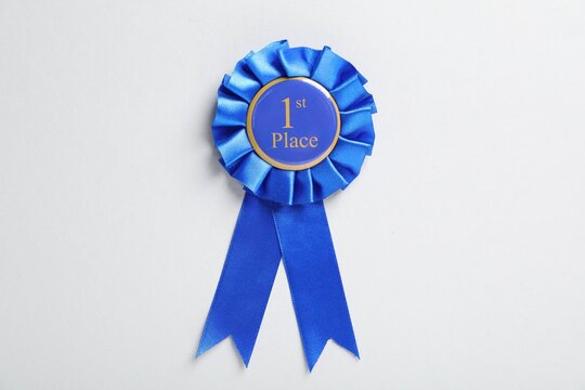 Blue award ribbon on light grey background, top view