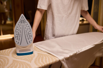 A person meticulously ironing clothes at home, ensuring all garments are neat and well cared for