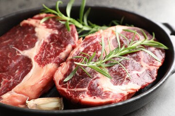 Pieces of raw beef meat and spices in baking dish on gray table, closeup