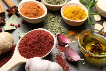 Different spices and oil on grey table, closeup