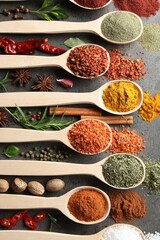 Many different spices in spoons on grey table, flat lay