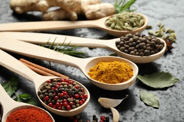 Many different spices in spoons on black table, closeup