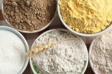 Different types of flour in bowls on table, top view