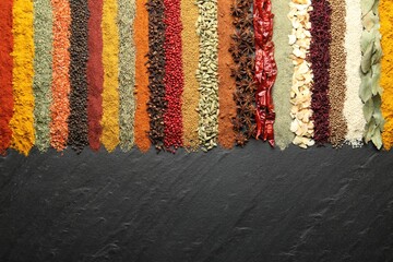 Many different spices on black table, flat lay. Space for text