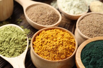 Different superfood powders on wooden table, closeup