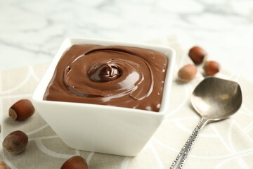 Tasty chocolate spread and hazelnuts on table, closeup