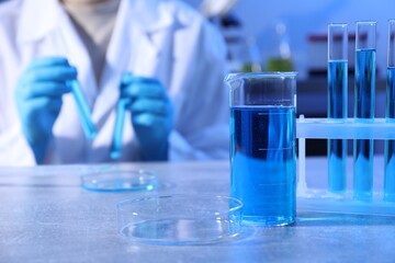 Petri dish and beaker with sample. Scientist working in laboratory, selective focus