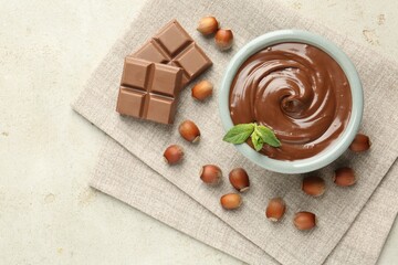 Tasty chocolate spread, pieces, mint and hazelnuts on light table, flat lay