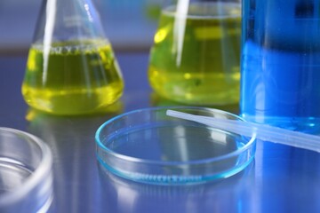 Petri dish, pipette and flasks with samples on table, closeup