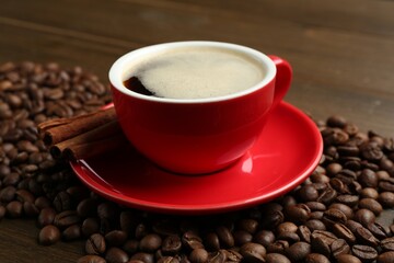 Aromatic coffee in cup, beans and cinnamon on wooden table, closeup
