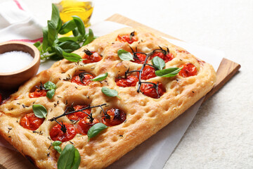 Delicious focaccia with tomatoes and spices on beige textured table, closeup