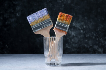 Brushes with color paints in glass on grey table
