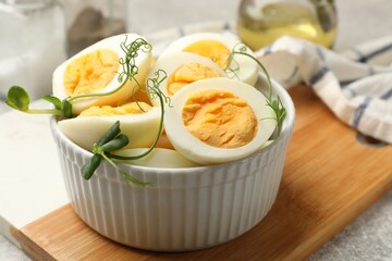 Hard boiled eggs with microgreens on grey table, closeup