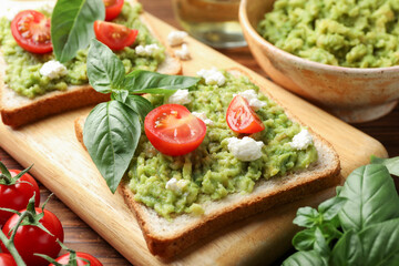 Delicious sandwiches with avocado, tomatoes, basil and cheese on table, closeup
