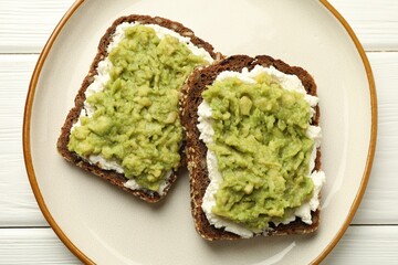 Delicious sandwiches with avocado and cream cheese on white wooden table, top view
