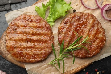 Delicious hamburger patties and spices on black table, top view