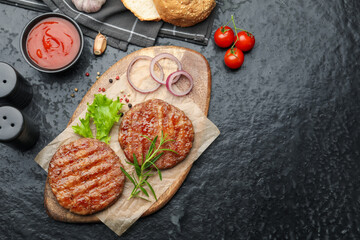 Delicious hamburger patties, tomatoes and spices on black table, flat lay