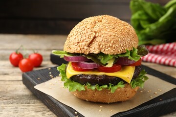 Delicious hamburger with patty and cheese on wooden table, closeup